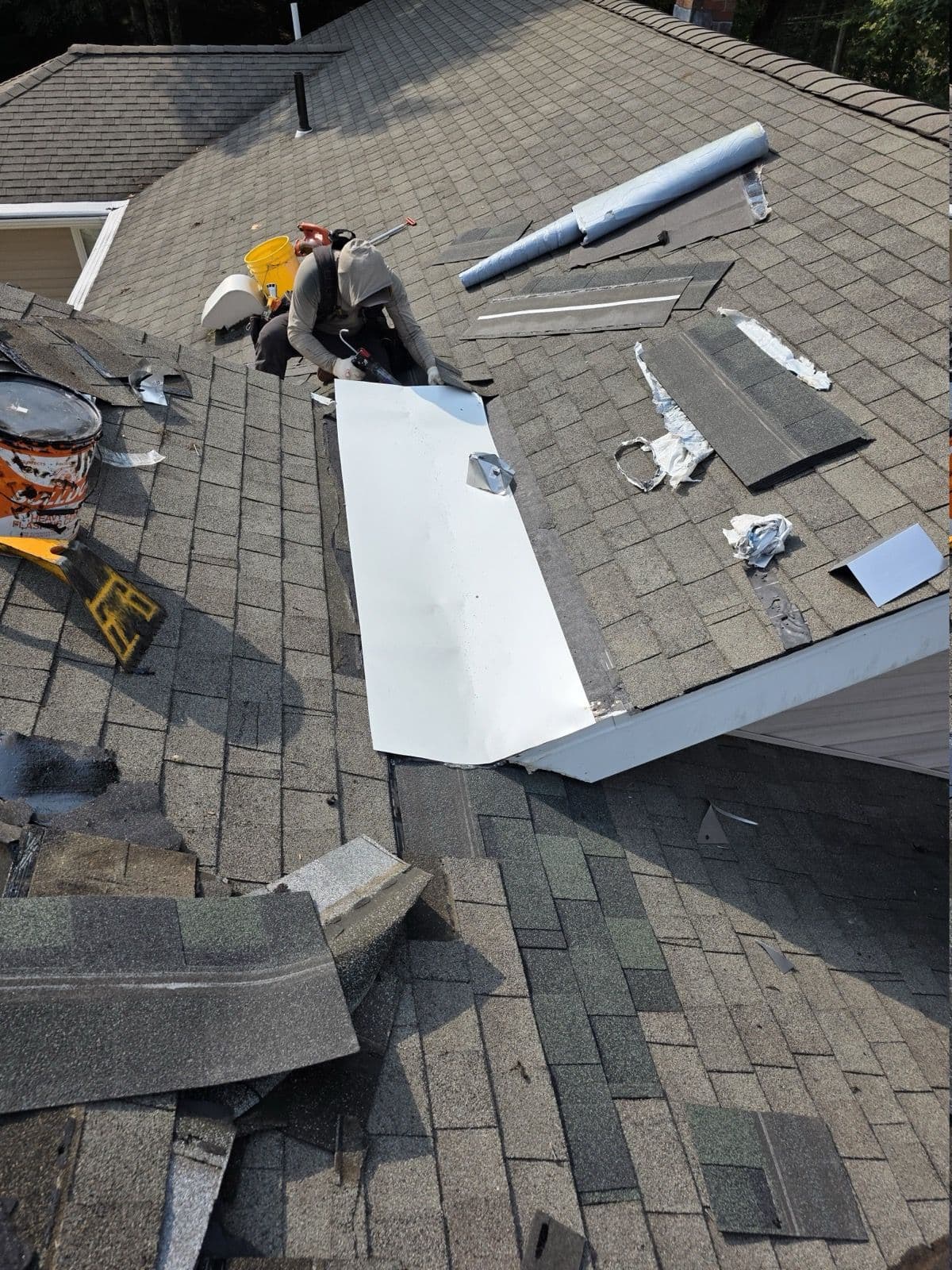 Crew member working on flashing and underlayment beside a wall