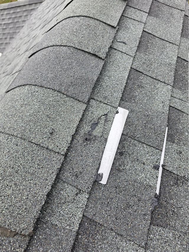 Torn gray shingle surface exposing the mat and old sealant in Suffield