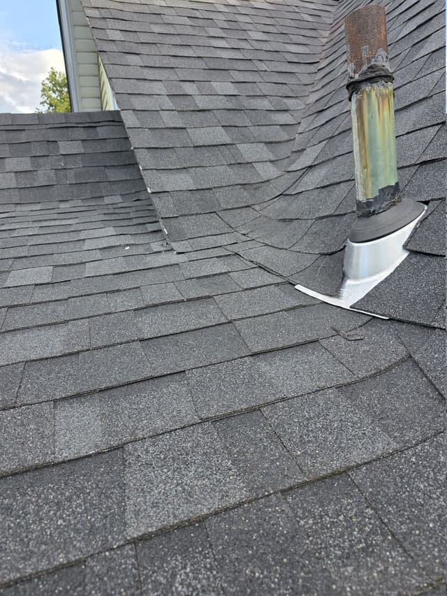Metal flashing base and rubber collar around a roof vent pipe