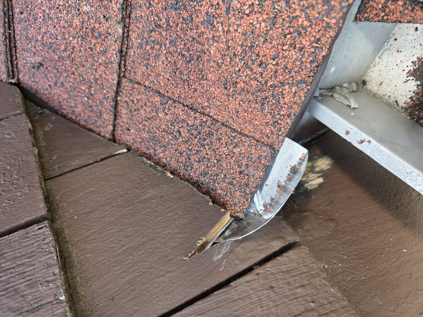 Close-up of metal flashing where roof shingles meet a shake wall during Trust Proof repair work