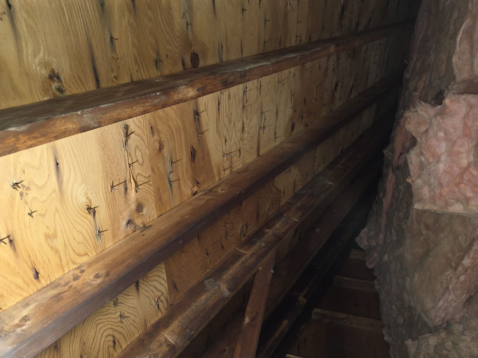 Attic side of the roof deck: plank decking with nail points coming through, checked from below before the repair.