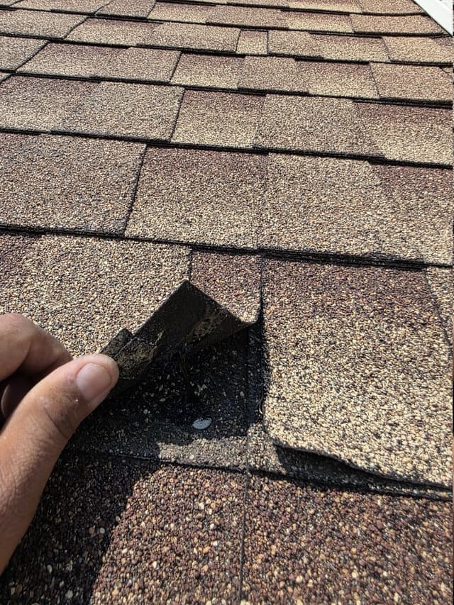 Cracked shingle tab with old sealant visible underneath