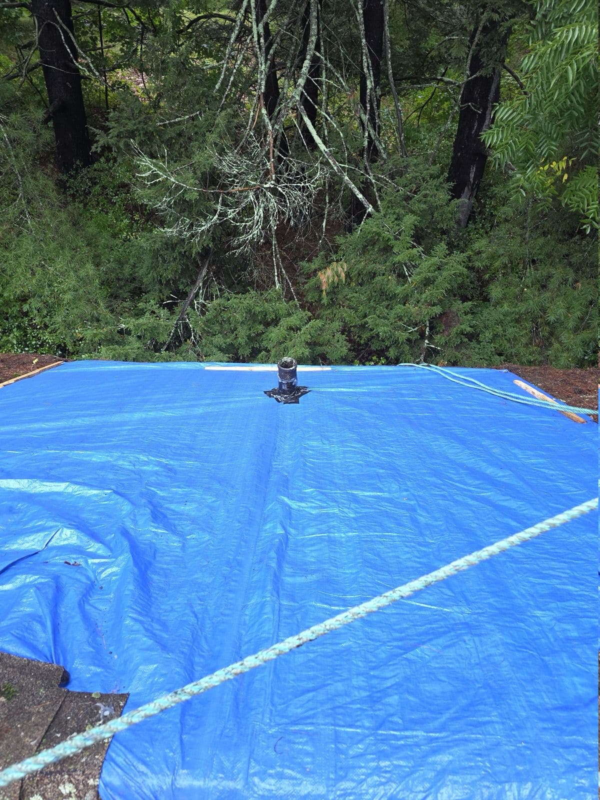 Blue roof tarp secured around a vent pipe