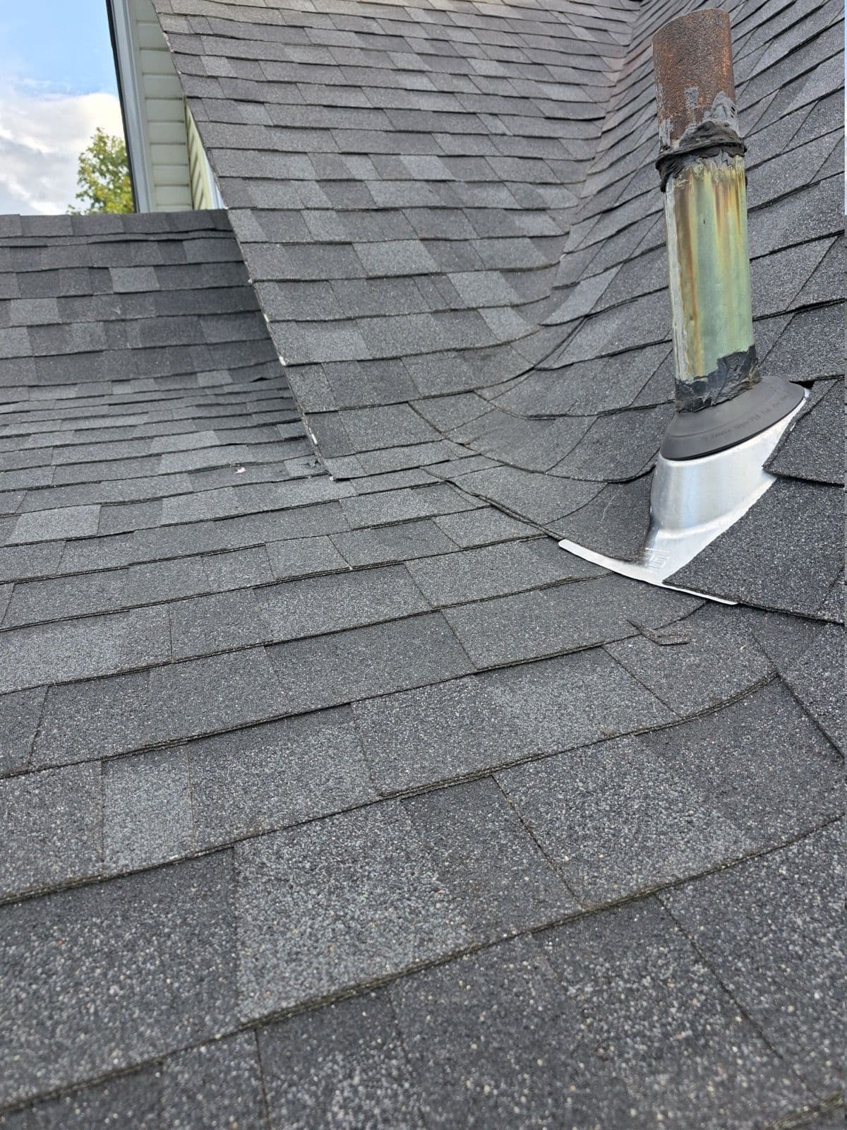 Metal flashing base and rubber collar around a roof vent pipe