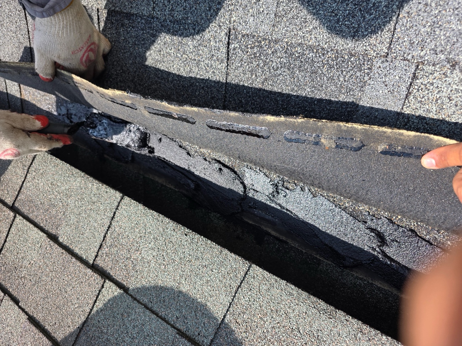 Roofer sealing fasteners under a lifted shingle during a Suffield, CT roof repair